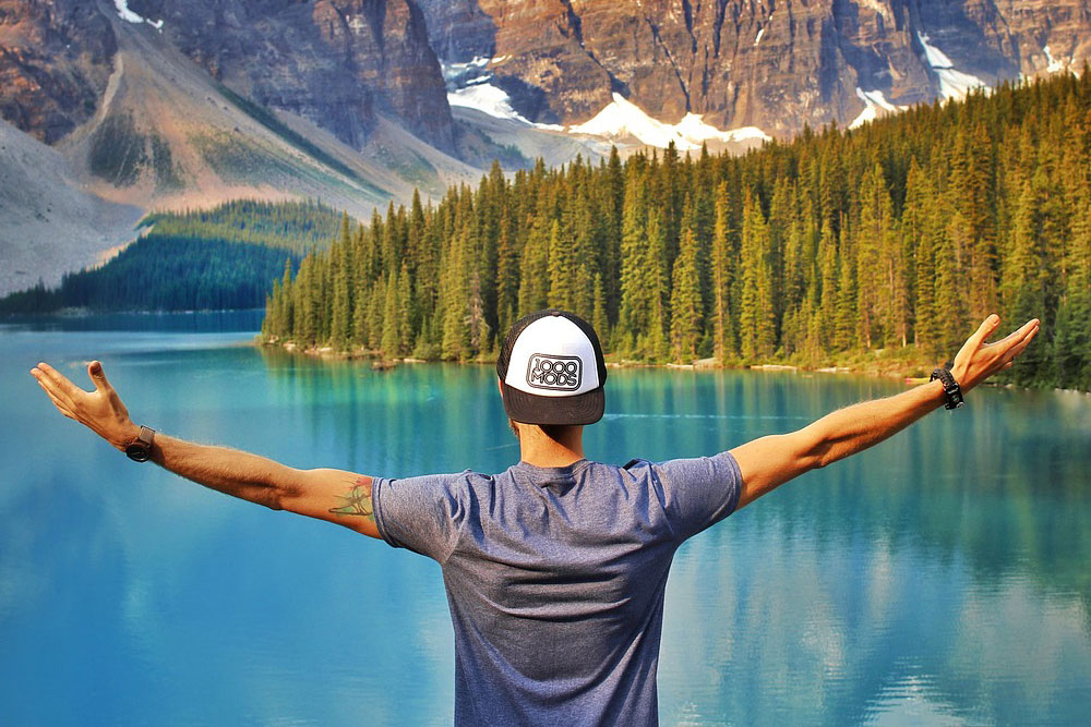 Man With Arms Raises In Front Of Lake